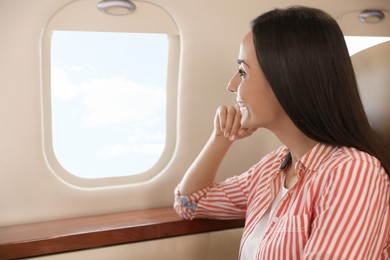 Photo of Young woman looking out window in airplane during flight