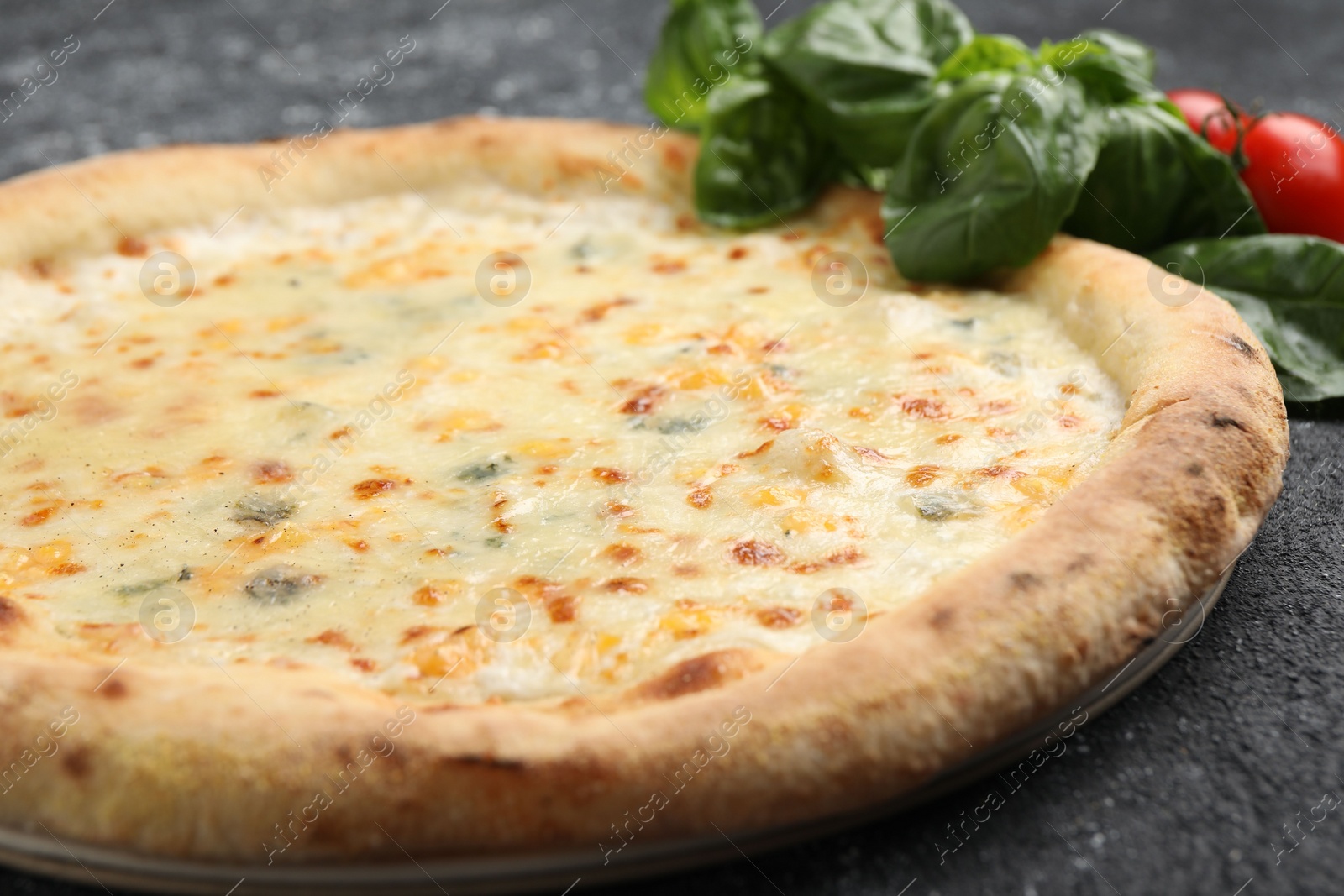 Photo of Delicious cheese pizza, basil and tomatoes on black textured table, closeup