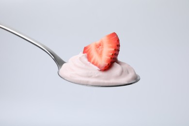 Delicious natural yogurt with fresh strawberry in spoon on light background