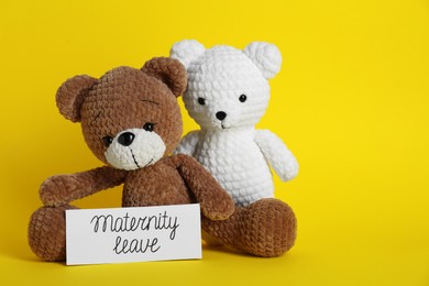 Toy bears and card with phrase Maternity Leave on yellow background. Space for text