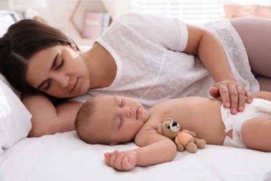 Mother with her cute baby sleeping on bed at home