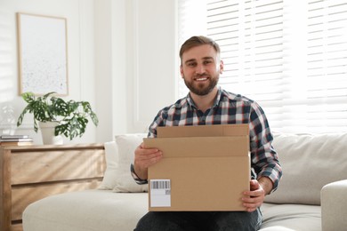 Happy young man with parcel at home