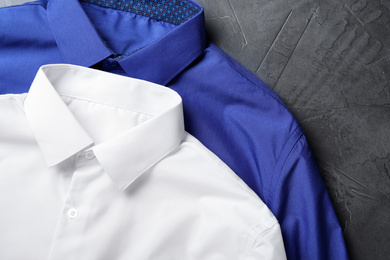 Photo of Stylish shirts on grey stone table, closeup. Dry-cleaning service