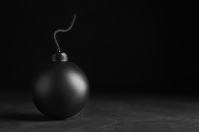 Sphere shaped bomb with burning fuse on black background. Space for text