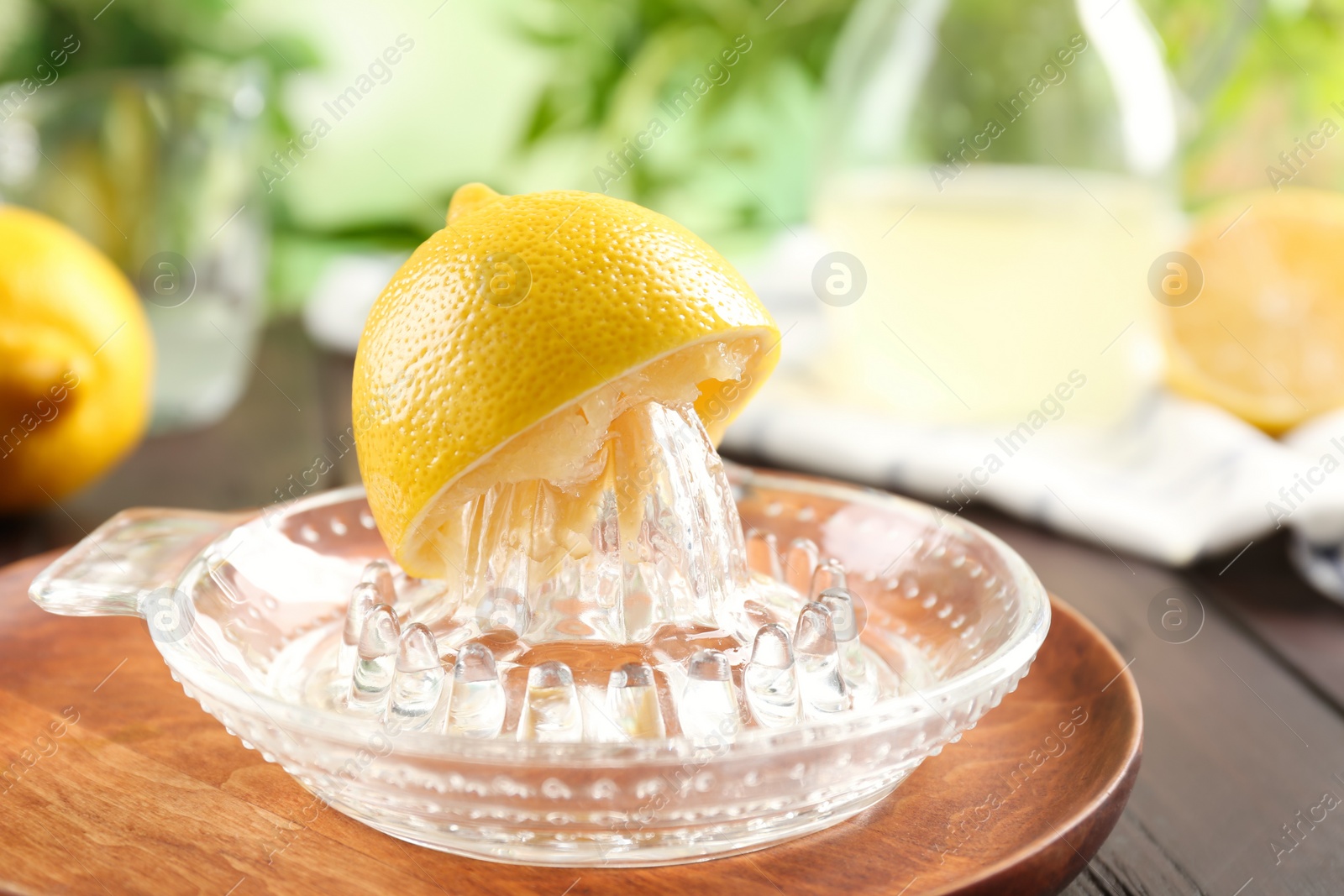 Photo of Glass citrus squeezer with lemon half on wooden plate