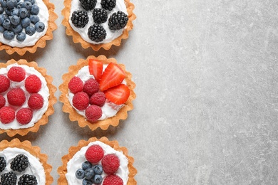 Many different berry tarts on table, flat lay with space for text. Delicious pastries