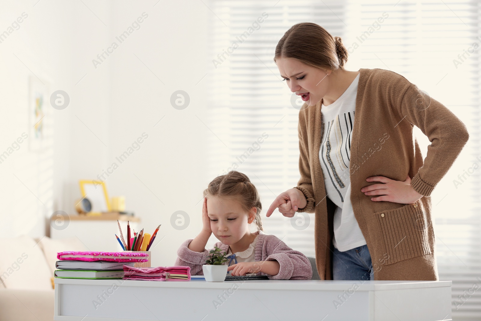 Photo of Mother scolding her daughter while helping with homework indoors