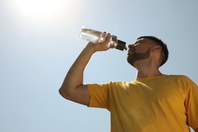 Photo of Man drinking water to prevent heat stroke outdoors, low angle view