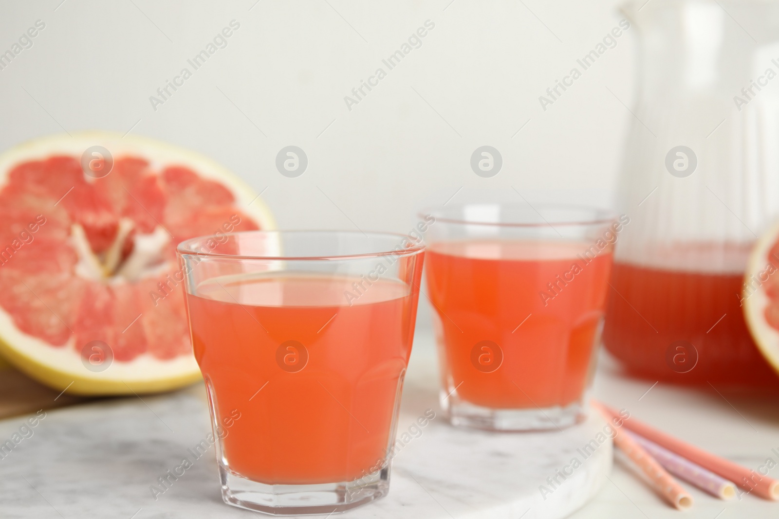Photo of Glasses of pink pomelo juice on white table