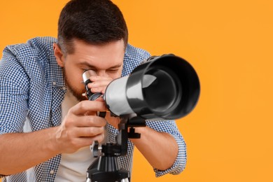 Astronomer looking at stars through telescope on orange background