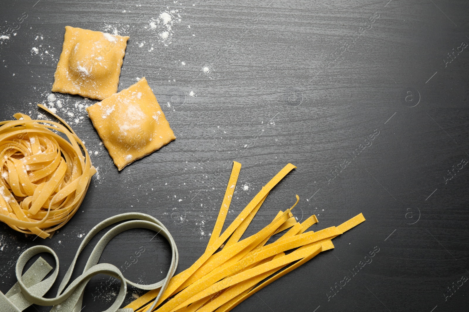 Photo of Flat lay composition with different types of pasta on black wooden table