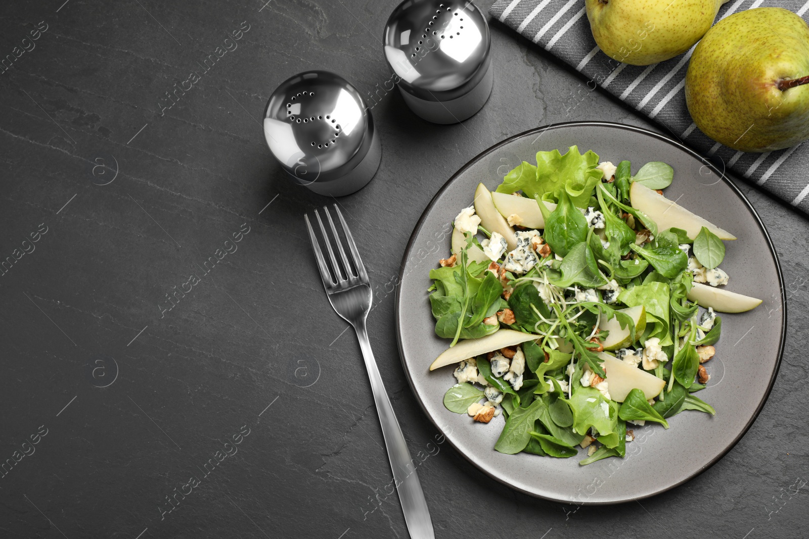 Photo of Tasty salad with pear slices served on black table, flat lay. Space for text