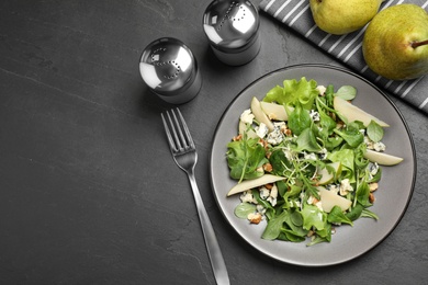 Photo of Tasty salad with pear slices served on black table, flat lay. Space for text