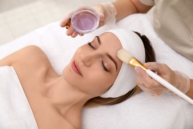 Young woman during face peeling procedure in salon