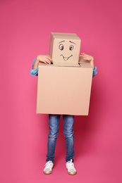 Cute little child in cardboard costume on color background