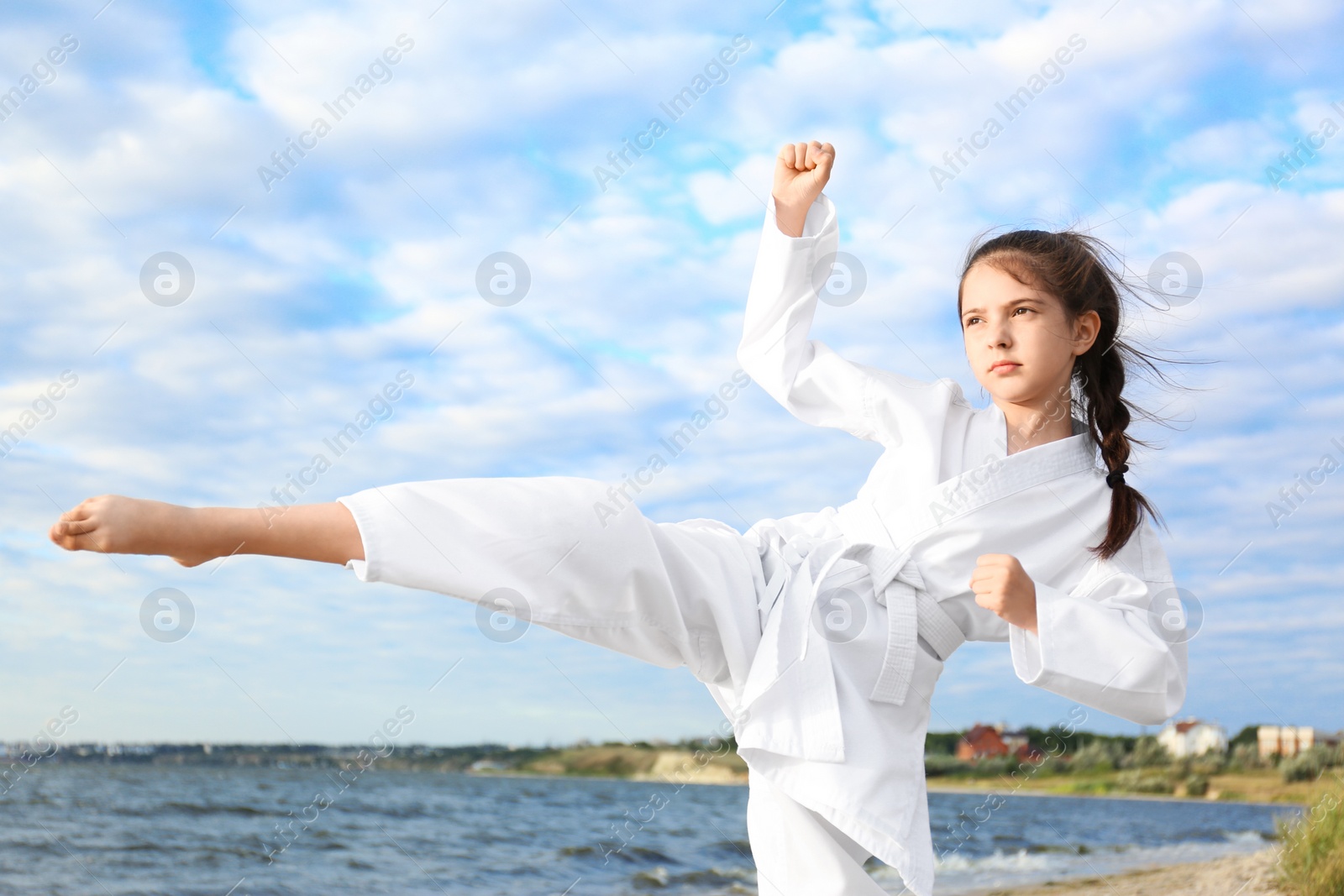 Photo of Cute little girl in kimono practicing karate near river