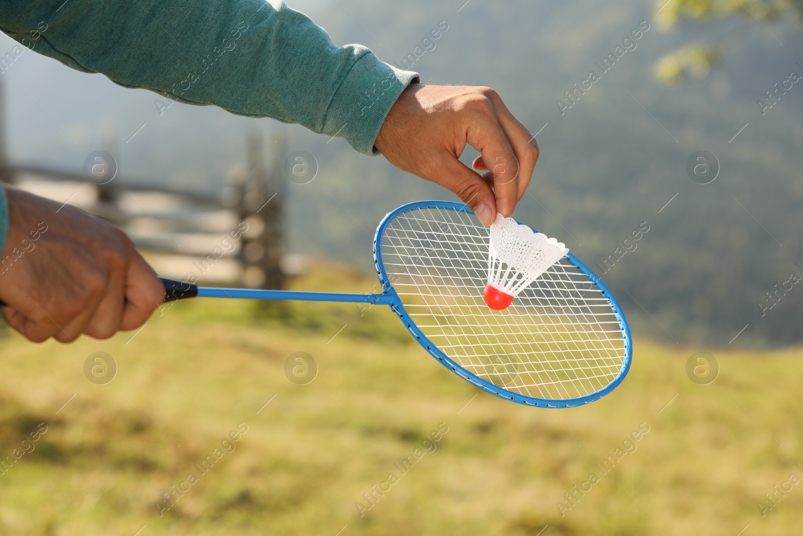 Photo of Man playing badminton outdoors on sunny day, closeup
