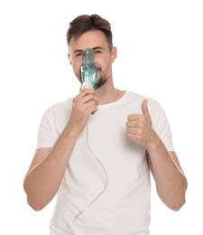 Photo of Man using nebulizer for inhalation and showing thumb up on white background