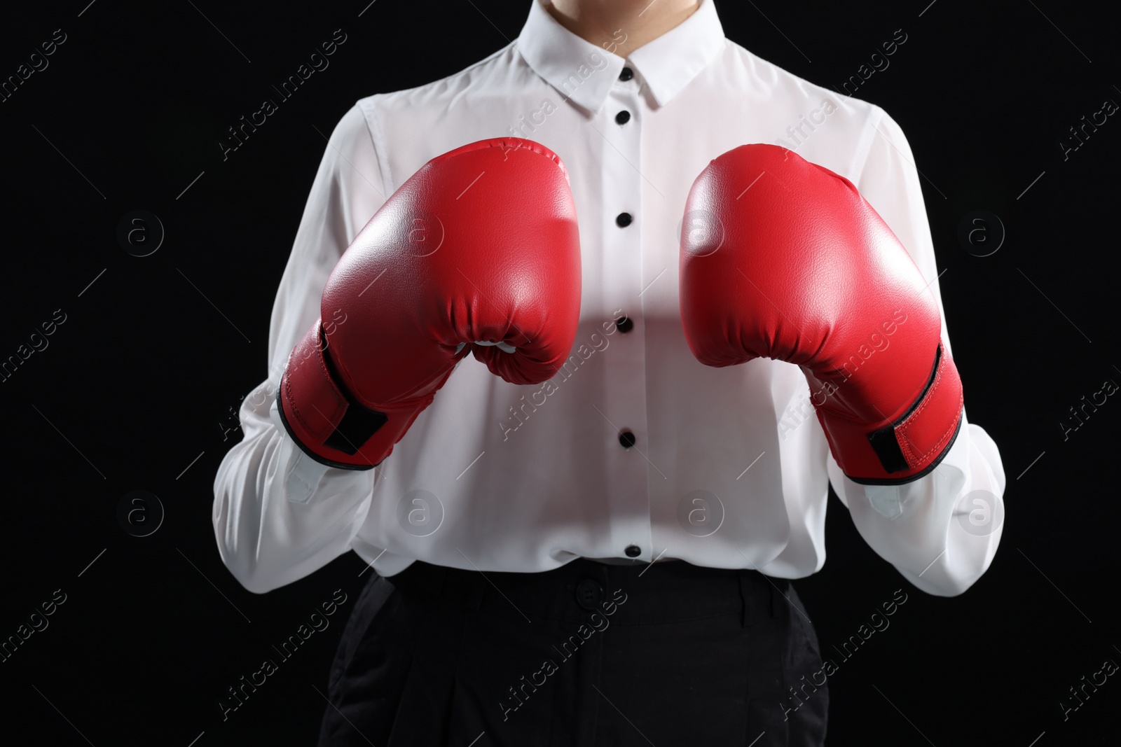 Photo of Businesswoman in shirt wearing boxing gloves on black background, closeup