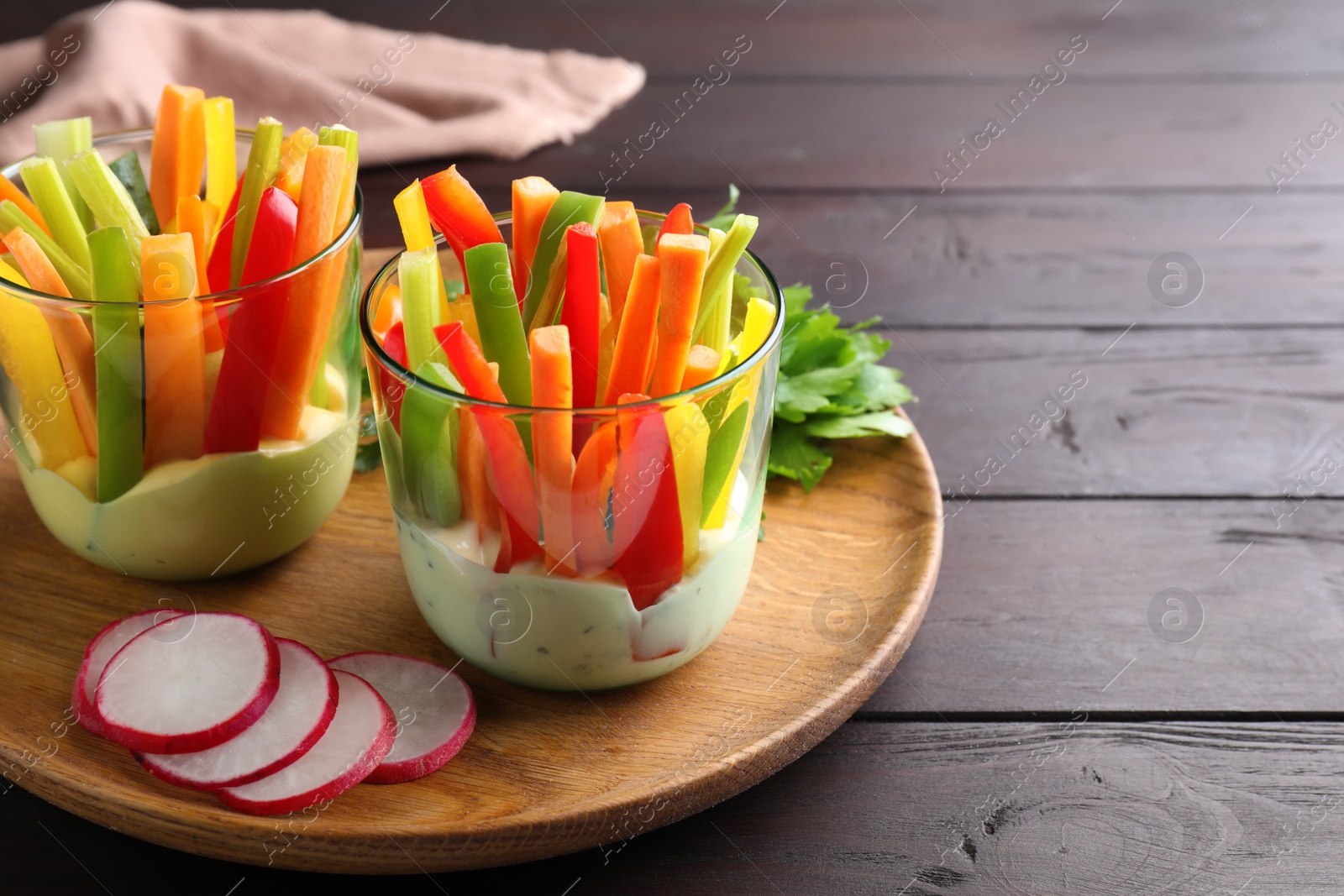 Photo of Fresh raw vegetable sticks with sauce on wooden table, space for text