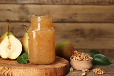 Photo of Delicious pear jam and fresh fruits on wooden table. Space for text