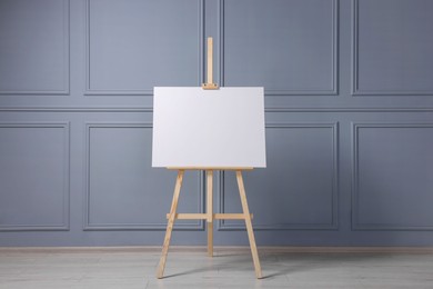 Photo of Wooden easel with blank canvas near grey wall indoors