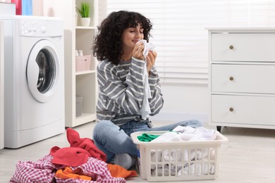 Photo of Beautiful woman with clean laundry at home