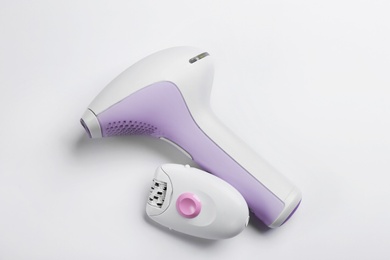 Modern devices for epilation on white background, top view