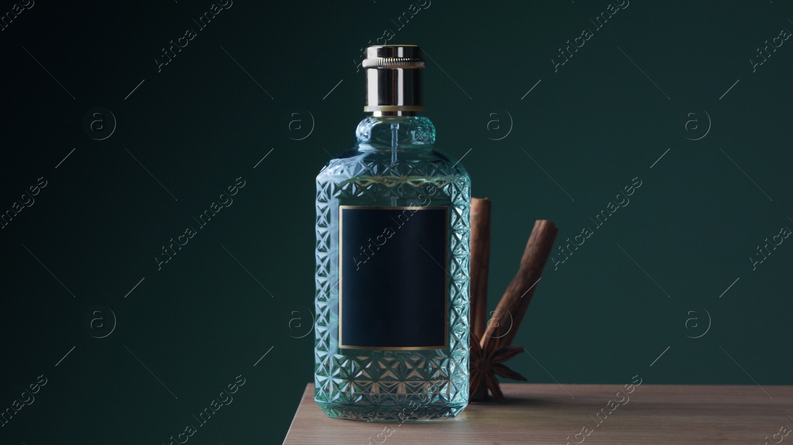 Photo of Bottle of perfume and different spices on wooden table. Space for text