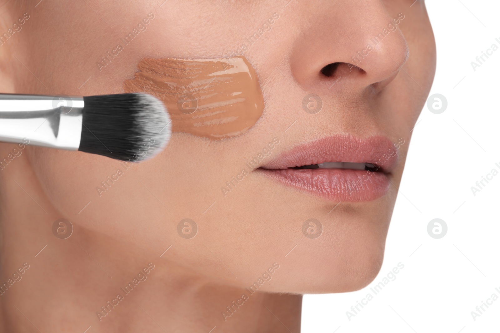 Photo of Woman applying foundation on face with brush against white background, closeup