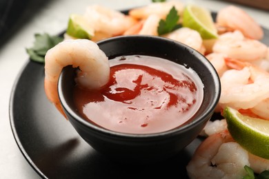 Photo of Tasty boiled shrimps with cocktail sauce, parsley and lime on light grey table, closeup