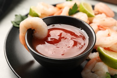 Tasty boiled shrimps with cocktail sauce, parsley and lime on light grey table, closeup