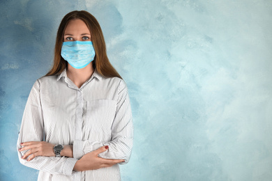 Photo of Woman with disposable mask on face against light blue background. Space for text