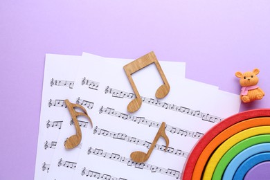 Wooden notes, music sheets and toys on violet background, top view. Baby song concept