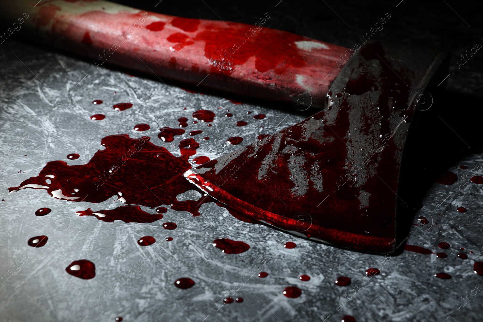 Photo of Axe with blood on dark gray textured surface, closeup