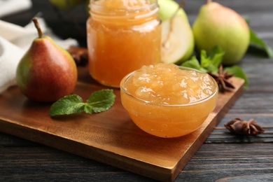 Photo of Delicious pear jam and fresh fruit on black wooden table