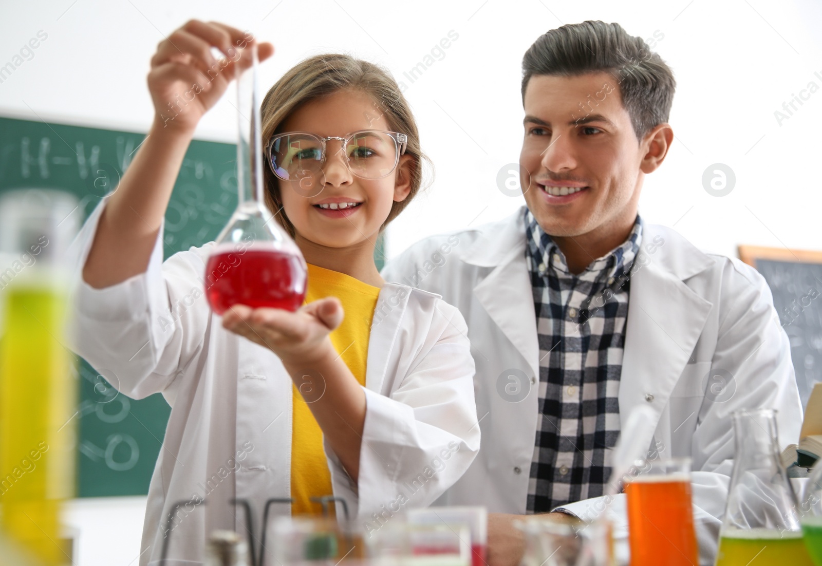 Photo of Teacher with pupil making experiment in chemistry class