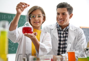 Teacher with pupil making experiment in chemistry class