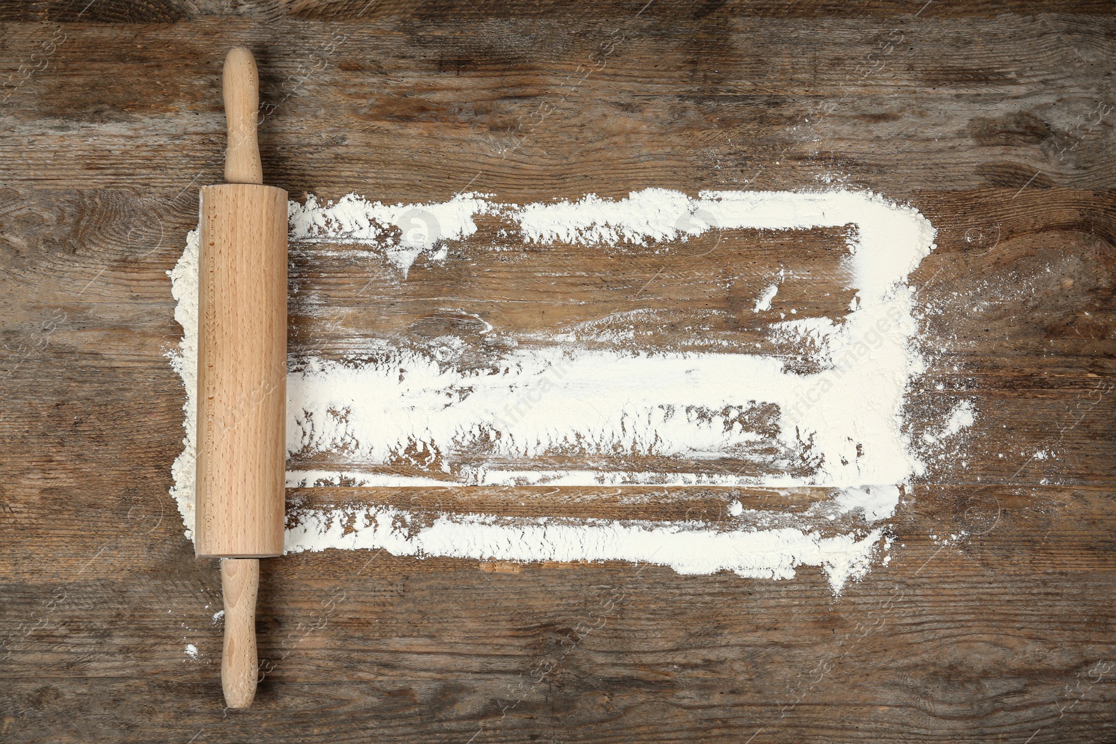 Photo of Flour and rolling pin on wooden table, flat lay