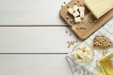 Photo of Cut tofu and soya beans on white wooden table, flat lay. Space for text