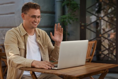 Photo of Handsome man working on laptop at table in outdoor cafe