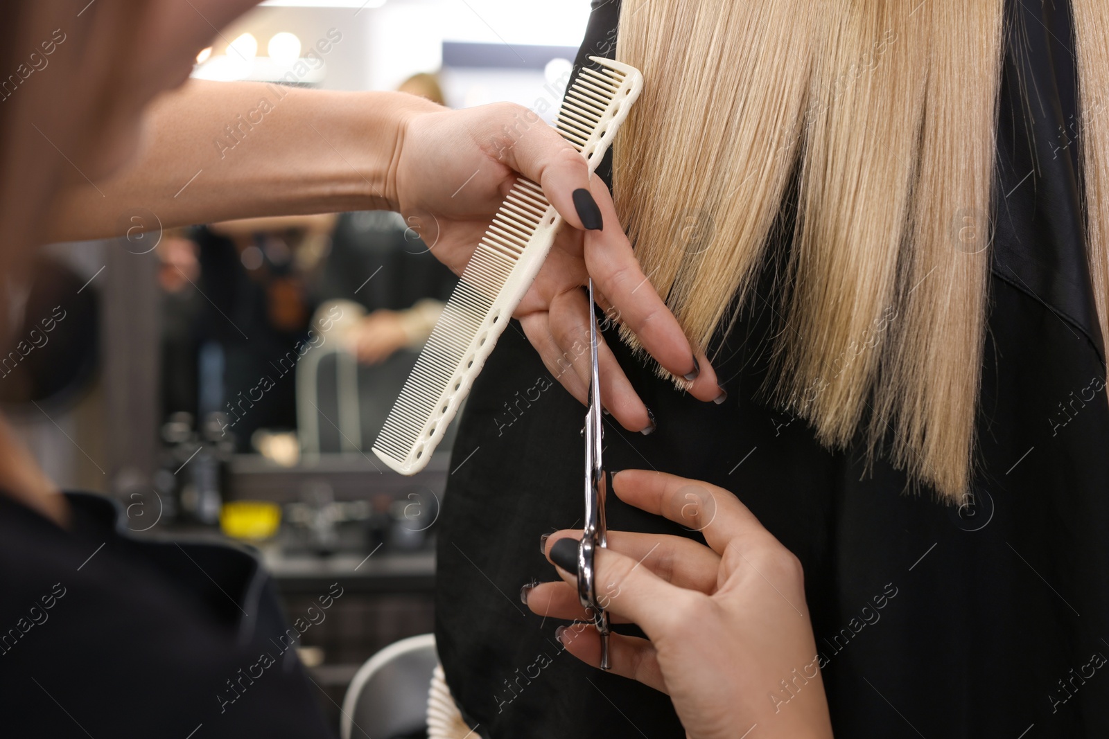 Photo of Professional hairdresser cutting woman's hair in salon, closeup