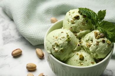 Photo of Tasty pistachio ice cream with mint on marble table, closeup view