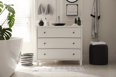 Photo of Stylish mat with pattern near chest of drawers in bathroom