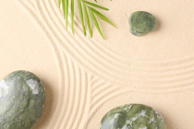 Photo of Zen concept. Stones, leaves and pattern on beige sand, flat lay. Space for text