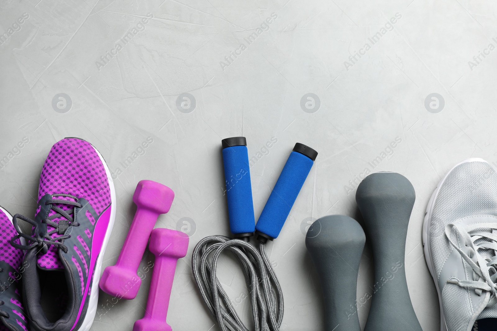 Photo of Flat lay composition with jump rope, gym equipment and space for text on grey background