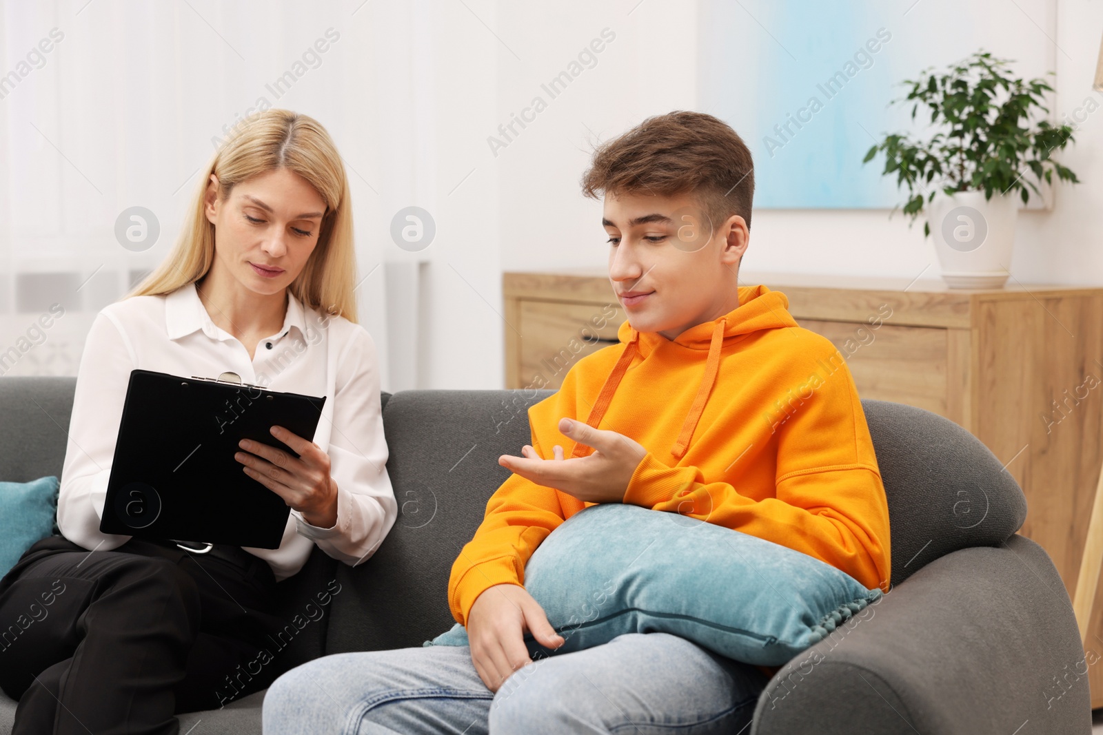 Photo of Psychologist working with teenage boy on sofa in office