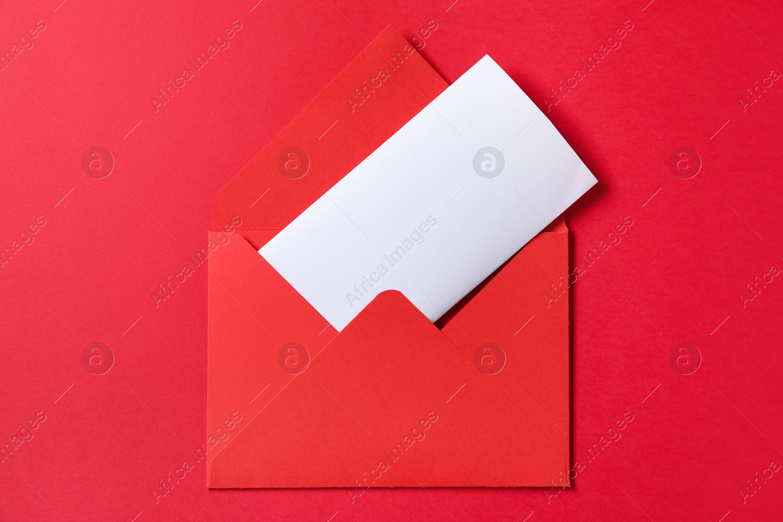 Photo of Letter envelope with card on red background, top view