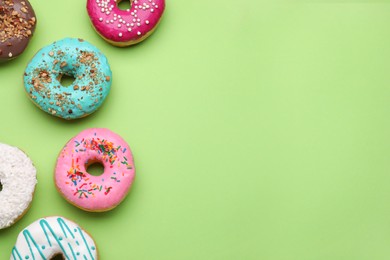 Photo of Different tasty glazed donuts on green background, flat lay. Space for text