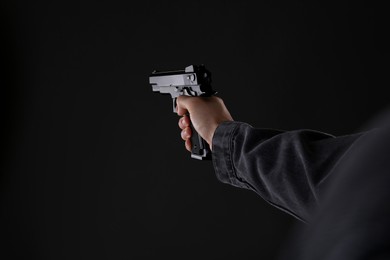 Man holding gun on black background, closeup